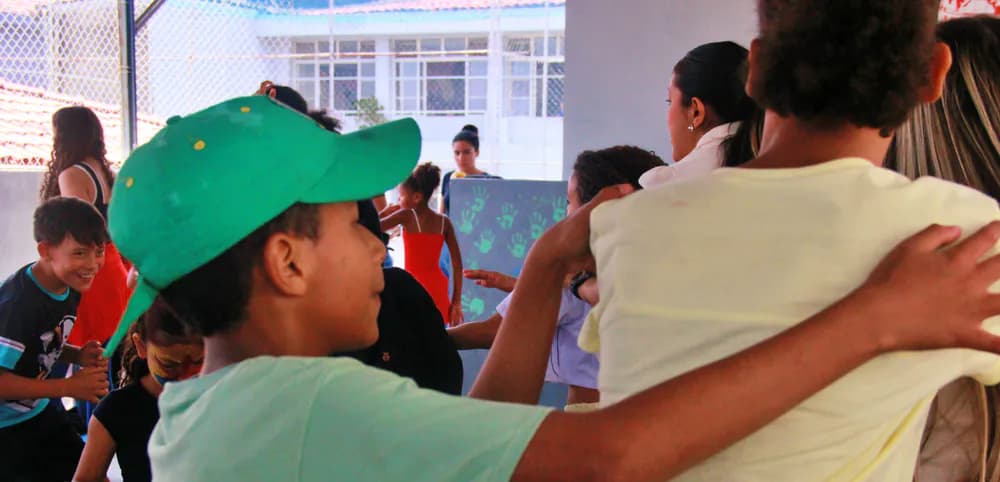 Crianças em fila com as mãos nos ombros umas das outras durante uma brincadeira no pátio